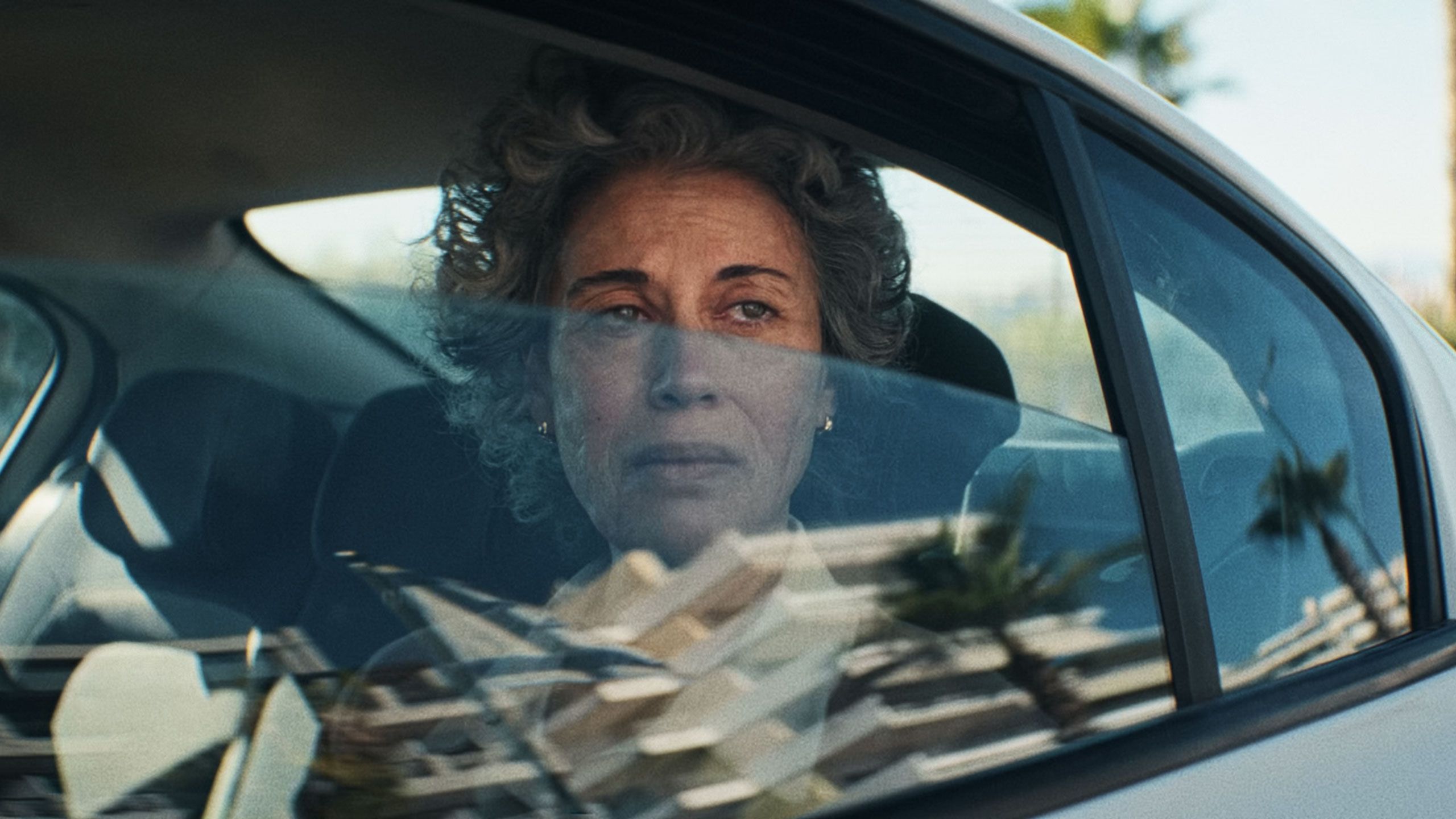 Woman looking out the car window looking sad.
