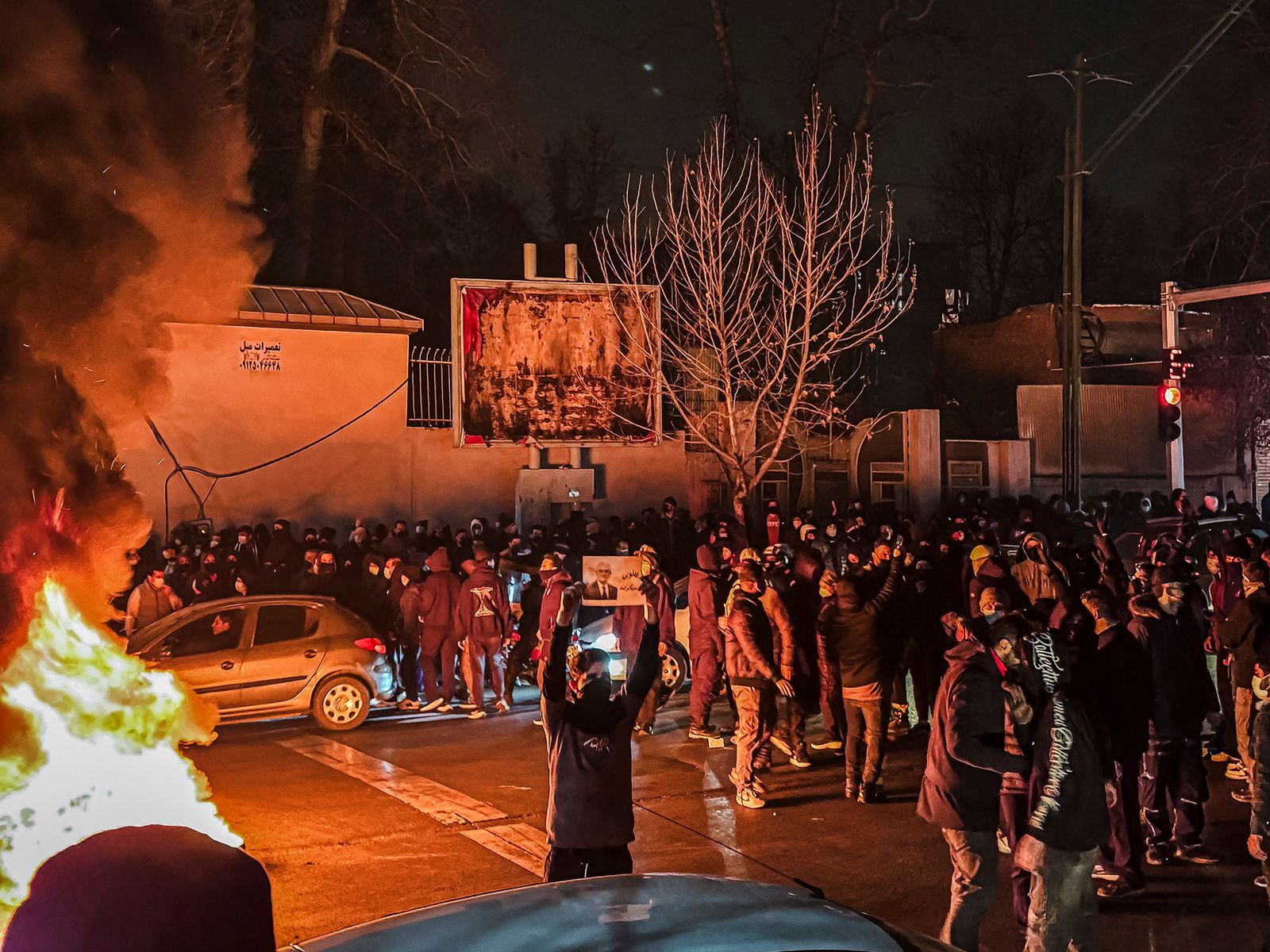 A group of protesters in Iran with flames on the left flank of the image.